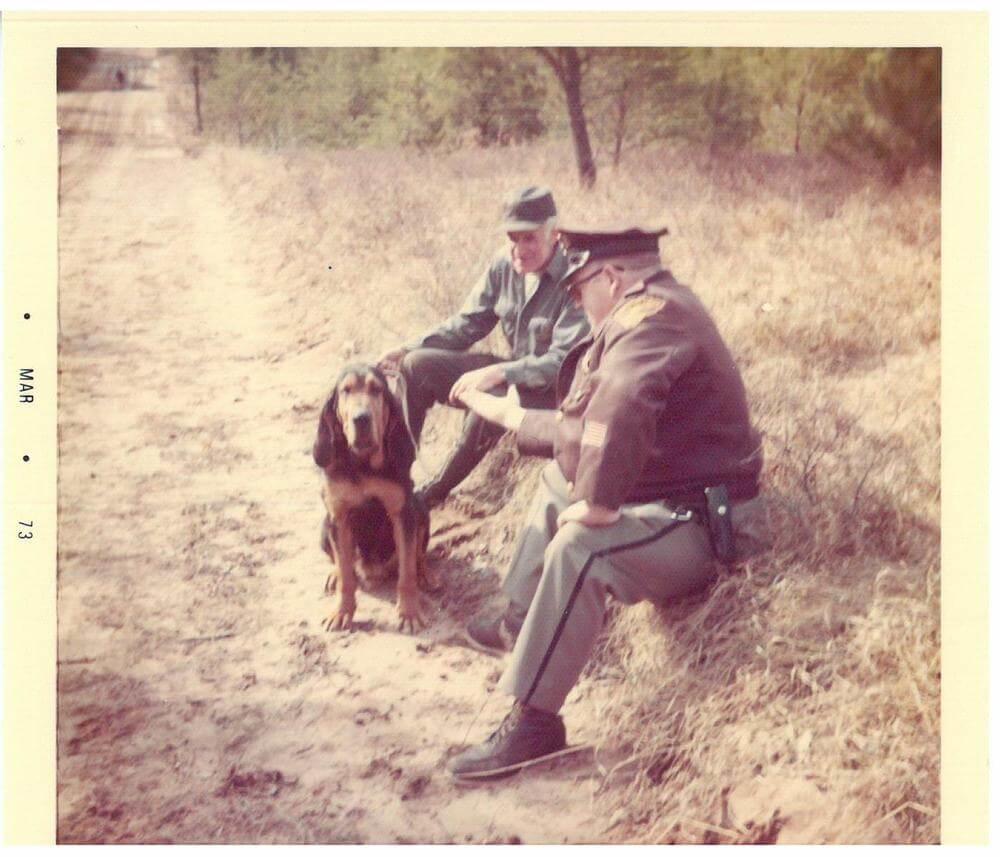 Officers sitting on the ground petting their K-9