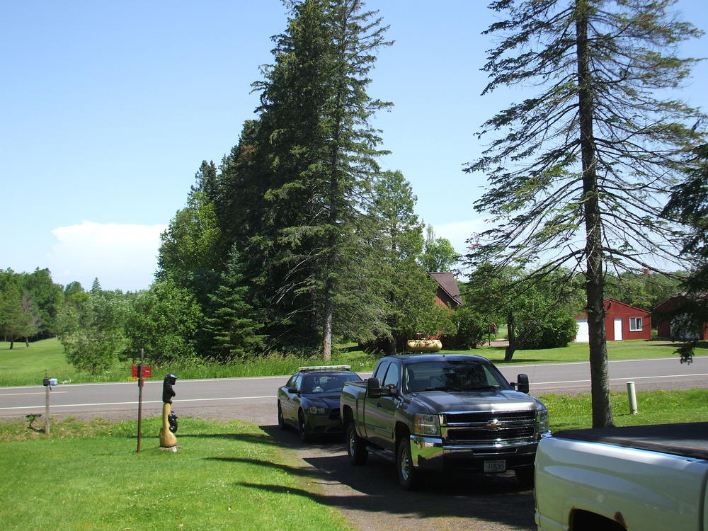 patrol vehicle parked in the driveway behind two pickup trucks