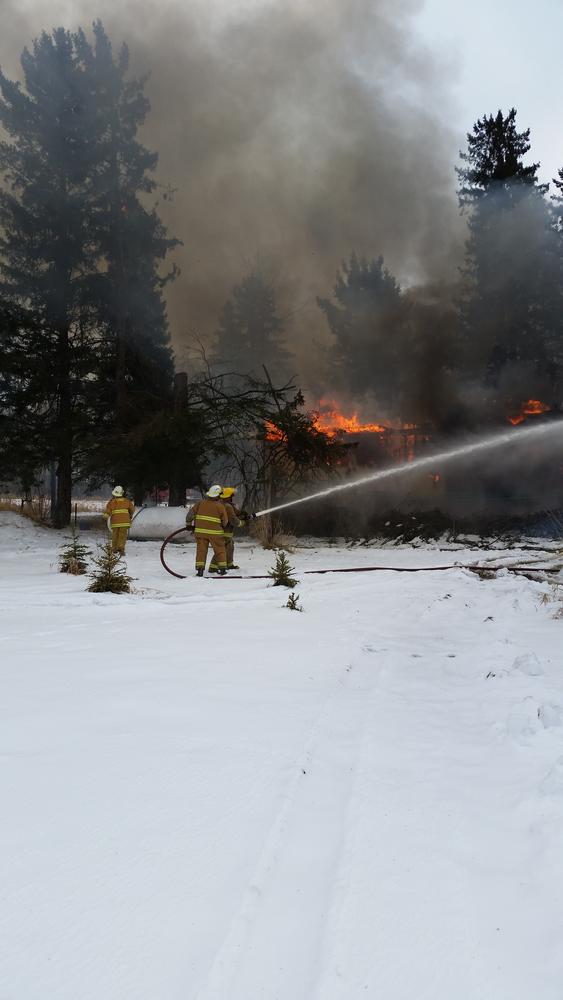 firefighters with water hose spraying the flames