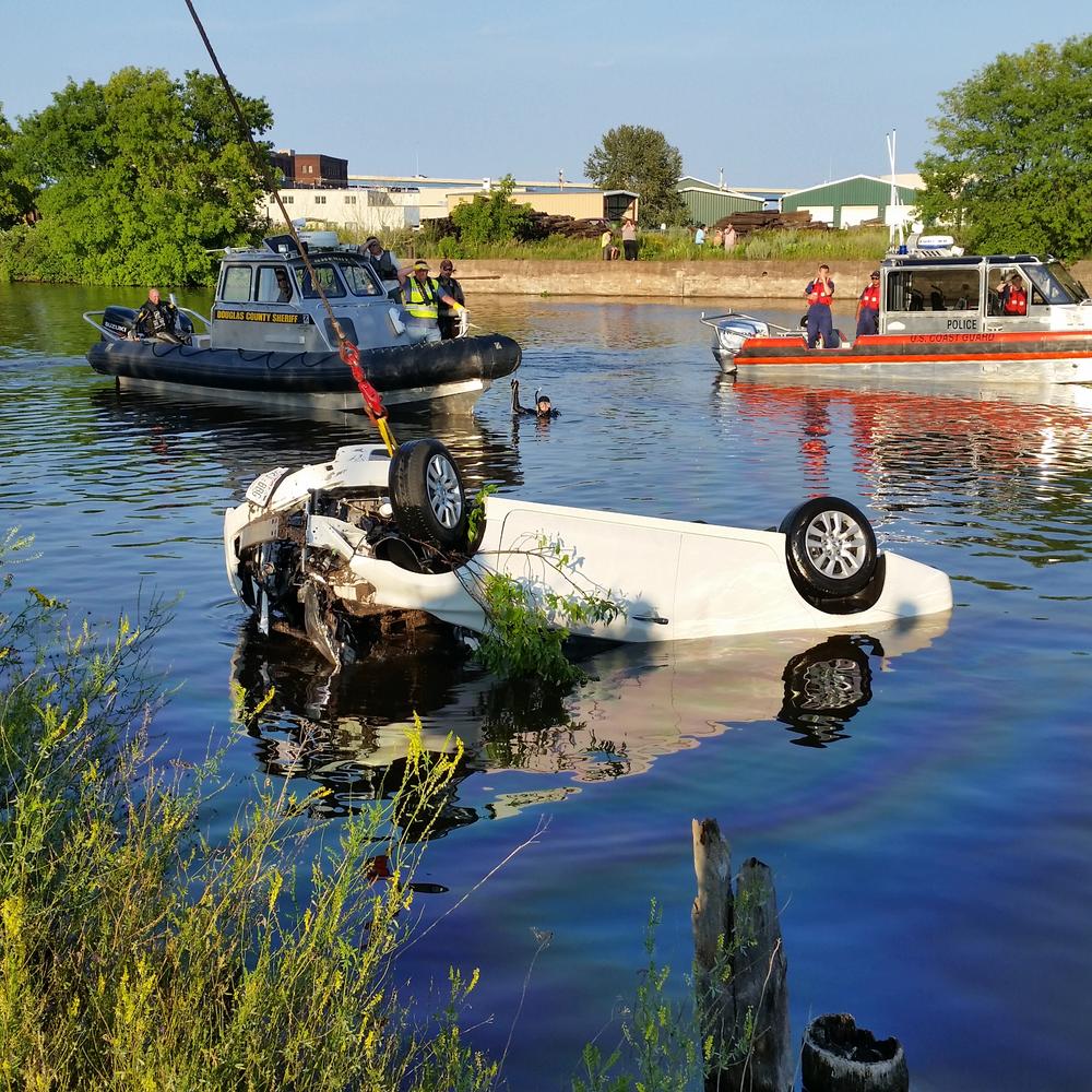 Crane pulling white vehicle from the water